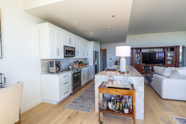 300 E 3rd St Unit 602, Little Rock, AR 72201 - kitchen with appliances with stainless steel finishes, light wood-type flooring, white cabinetry, open floor plan, and backsplash