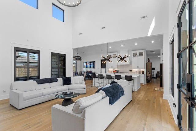 7509 S Shoreline, Benton, AR 72019 - living room featuring a chandelier, a towering ceiling, and light wood-style flooring