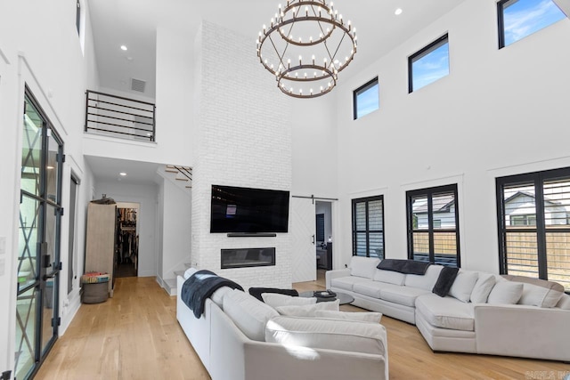 7509 S Shoreline, Benton, AR 72019 - living room featuring a high ceiling, a chandelier, a large fireplace, stairs, and light wood-style flooring