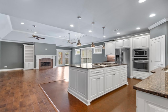 9 Bishop Pl, Little Rock, AR 72223 - kitchen with stainless steel appliances, a tray ceiling, crown molding, a ceiling fan, and white cabinetry