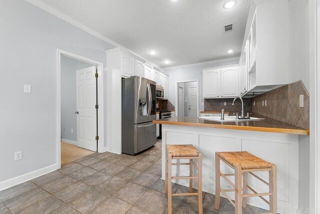 31 Auburn Hills Dr, Greenbrier, AR 72058 - kitchen featuring appliances with stainless steel finishes, a peninsula, ornamental molding, backsplash, and white cabinetry