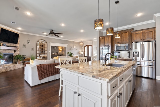 2705 Pulaski Dr, Conway, AR 72034 - kitchen with appliances with stainless steel finishes, open floor plan, a breakfast bar, a stone fireplace, and light stone countertops
