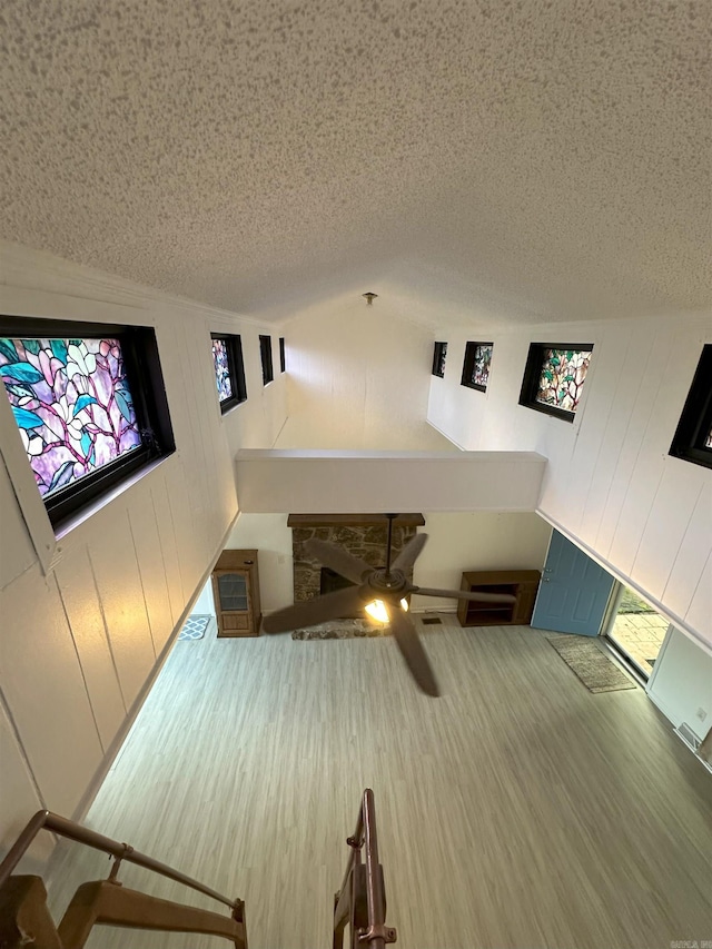 900 Davidson Cir, Edgemont, AR 72044 - unfurnished living room with a textured ceiling, wooden walls, ceiling fan, and healthy amount of natural light