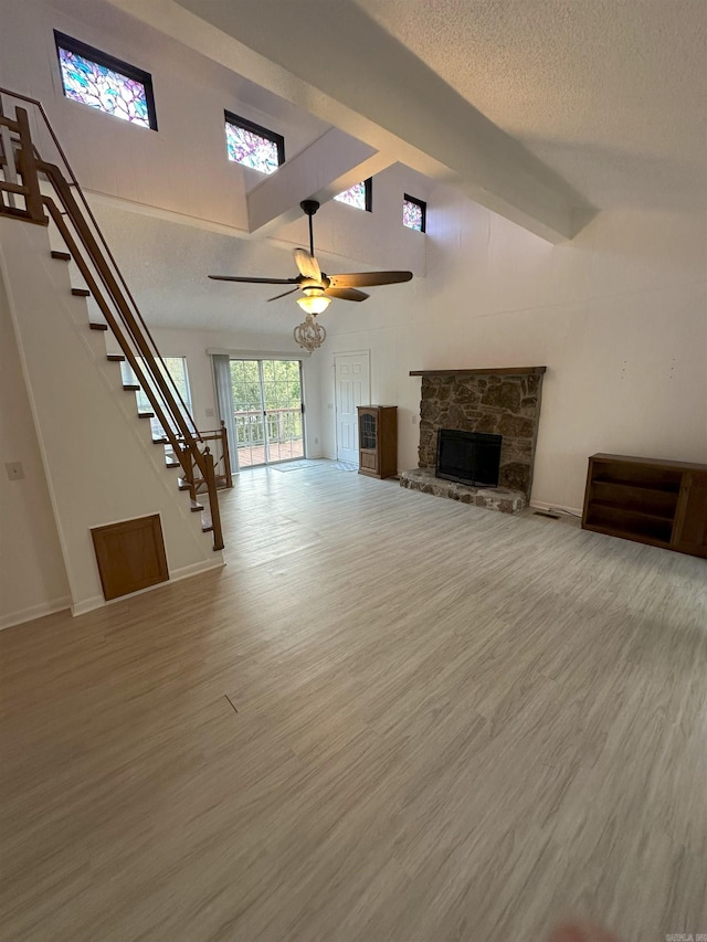 900 Davidson Cir, Edgemont, AR 72044 - unfurnished living room featuring stairs, wood finished floors, ceiling fan, a stone fireplace, and a textured ceiling