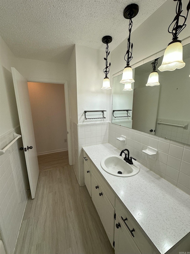 900 Davidson Cir, Edgemont, AR 72044 - bathroom with tile walls, wood finished floors, vanity, a textured ceiling, and wainscoting