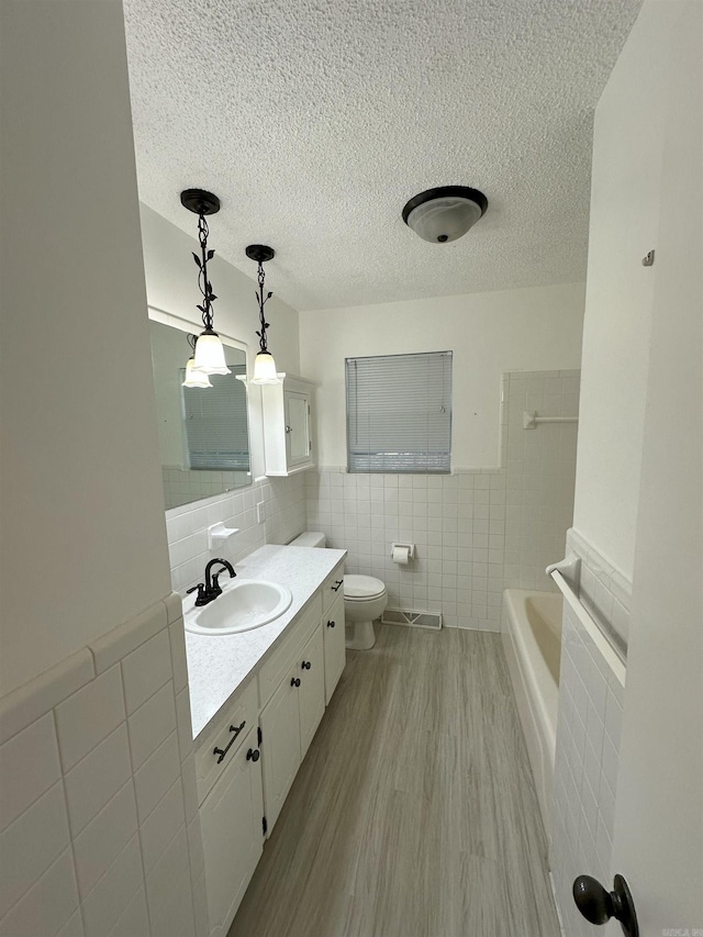 900 Davidson Cir, Edgemont, AR 72044 - full bathroom with tile walls, vanity, a tub, wood finished floors, and a textured ceiling