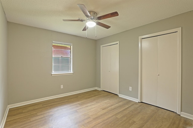6905 White Oak Cv, White Hall, AR 71602 - unfurnished bedroom featuring multiple closets, wood finished floors, a textured ceiling, and a ceiling fan