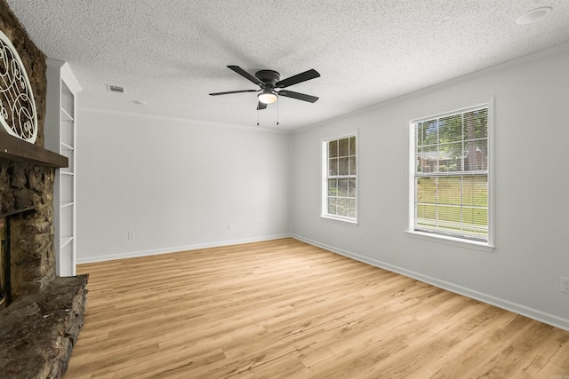 4901 Westwood Ave, Little Rock, AR 72204 - unfurnished living room featuring crown molding, light wood-style flooring, a ceiling fan, a stone fireplace, and a textured ceiling