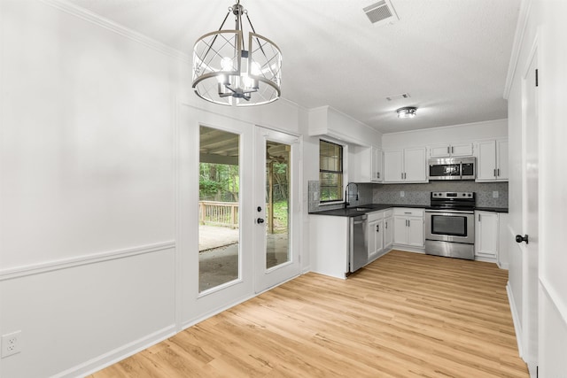 4901 Westwood Ave, Little Rock, AR 72204 - kitchen with stainless steel appliances, dark countertops, light wood-type flooring, white cabinets, and a chandelier
