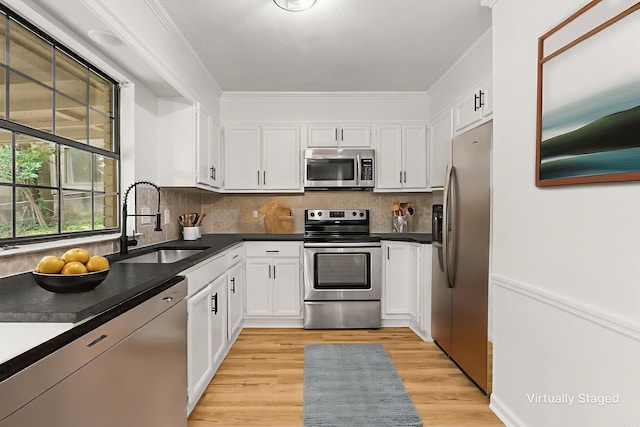 4901 Westwood Ave, Little Rock, AR 72204 - kitchen with appliances with stainless steel finishes, ornamental molding, white cabinetry, light wood-style floors, and dark countertops
