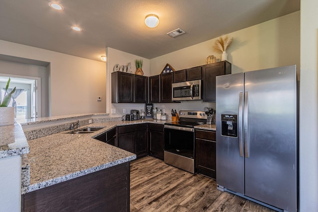 5244 Prospect Trl, Jonesboro, AR 72405 - kitchen with appliances with stainless steel finishes, dark wood-style floors, light stone countertops, dark brown cabinets, and a peninsula