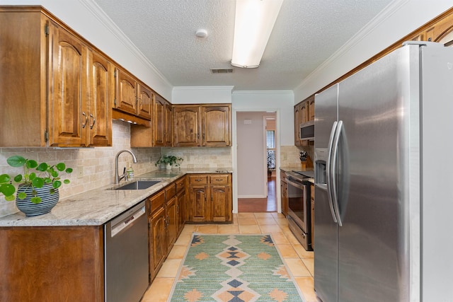 2608 Grist Mill Rd, Little Rock, AR 72227 - kitchen featuring stainless steel appliances, light tile patterned floors, backsplash, brown cabinetry, and a textured ceiling