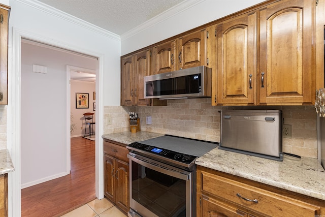 2608 Grist Mill Rd, Little Rock, AR 72227 - kitchen with appliances with stainless steel finishes, tasteful backsplash, crown molding, light stone countertops, and a textured ceiling