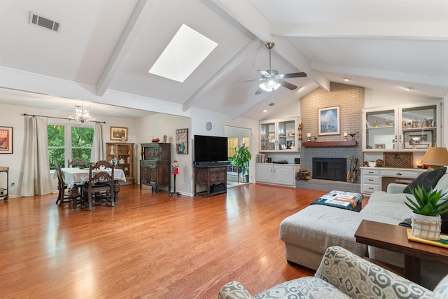 2608 Grist Mill Rd, Little Rock, AR 72227 - living room featuring a chandelier, a fireplace, a ceiling fan, a skylight, and light wood-type flooring