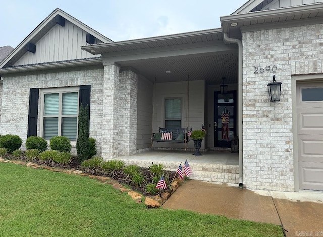 2690 Overcup Dr, Conway, AR 72034 - property entrance featuring board and batten siding, covered porch, a yard, brick siding, and a garage