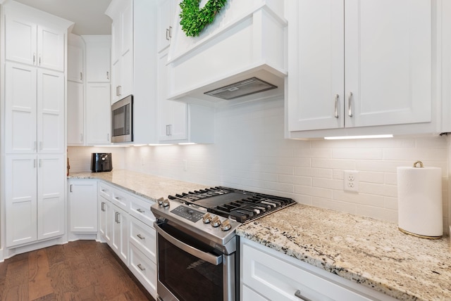 2690 Overcup Dr, Conway, AR 72034 - kitchen with gas stove, premium range hood, black microwave, white cabinetry, and tasteful backsplash