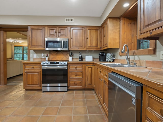 16 Almenara, Hot Springs Village, AR 71909 - kitchen with stainless steel appliances, brown cabinetry, tile countertops, recessed lighting, and backsplash