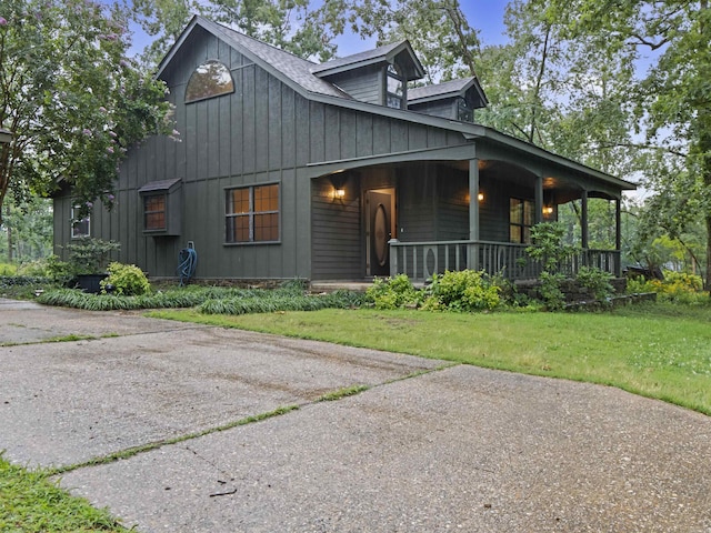 16 Almenara, Hot Springs Village, AR 71909 - view of front of house with covered porch, board and batten siding, and a front yard