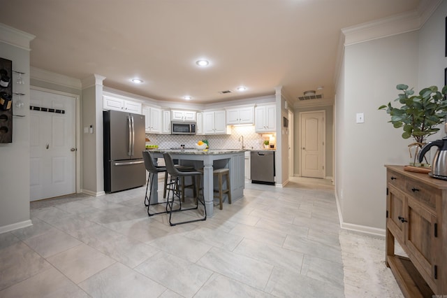 7139 Park Meadows Dr, Sherwood, AR 72120 - kitchen featuring appliances with stainless steel finishes, crown molding, a breakfast bar, tasteful backsplash, and white cabinetry