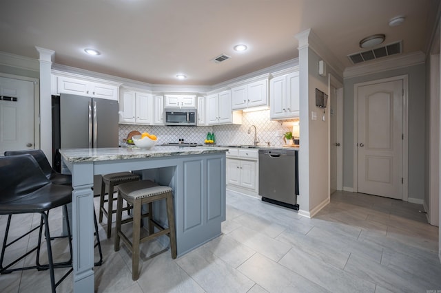 7139 Park Meadows Dr, Sherwood, AR 72120 - kitchen with appliances with stainless steel finishes, decorative backsplash, ornamental molding, a breakfast bar area, and white cabinetry