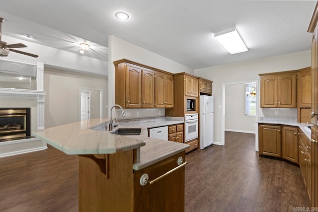 1226 Grayson Cir, Malvern, AR 72104 - kitchen featuring white appliances, a peninsula, dark wood-style floors, brown cabinets, and a breakfast bar area