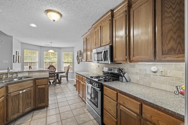 5132 Austin Lakes Cir, Sherwood, AR 72120 - kitchen with stainless steel appliances, brown cabinetry, backsplash, light tile patterned flooring, and a textured ceiling