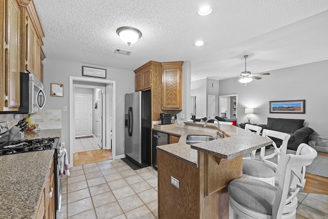 5132 Austin Lakes Cir, Sherwood, AR 72120 - kitchen with appliances with stainless steel finishes, a peninsula, a breakfast bar area, open floor plan, and brown cabinetry