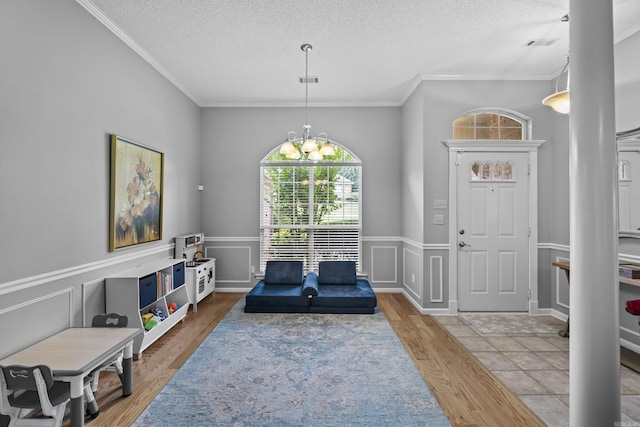 5132 Austin Lakes Cir, Sherwood, AR 72120 - entrance foyer featuring a textured ceiling, wood finished floors, crown molding, a chandelier, and wainscoting