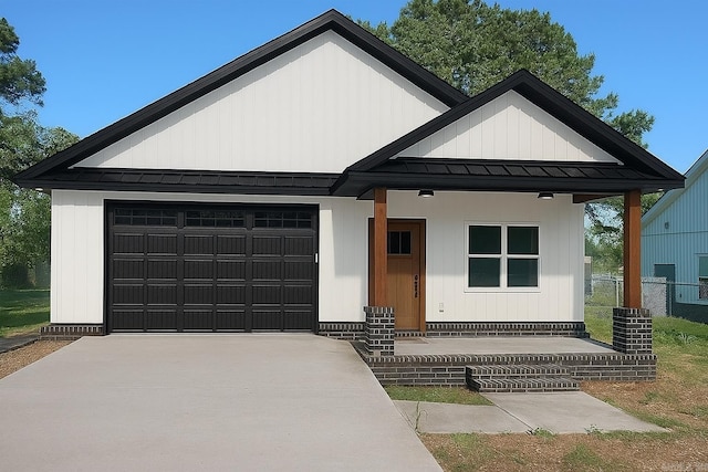 112 S Eagle, Sheridan, AR 72150 - view of front facade featuring a standing seam roof, concrete driveway, an attached garage, a metal roof, and a porch