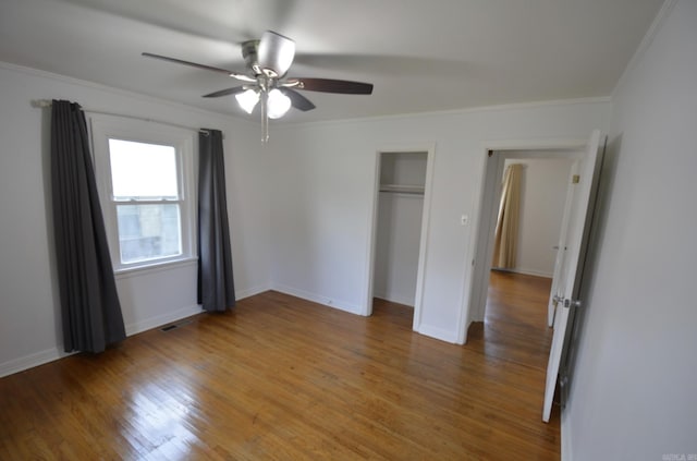 unfurnished bedroom with light wood-style flooring, crown molding, a closet, and a ceiling fan