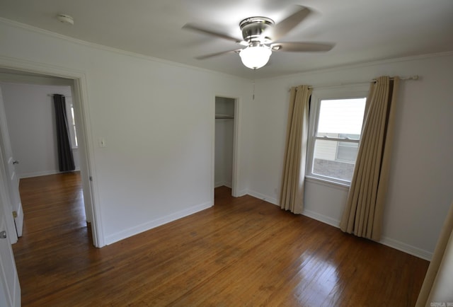 unfurnished bedroom with wood finished floors, a closet, crown molding, and a ceiling fan