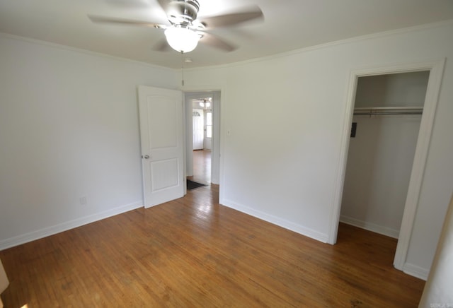 unfurnished bedroom with a closet, wood finished floors, crown molding, and a ceiling fan