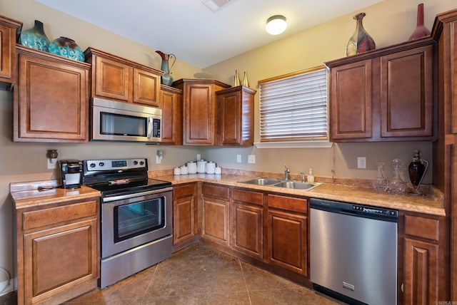 2355 Wilmington, Conway, AR 72034 - kitchen featuring stainless steel appliances, light countertops, dark tile patterned floors, and brown cabinetry
