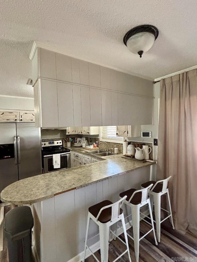 4 Paul St, Mcgehee, AR 71654 - kitchen featuring stainless steel appliances, a textured ceiling, a peninsula, a breakfast bar, and white cabinets