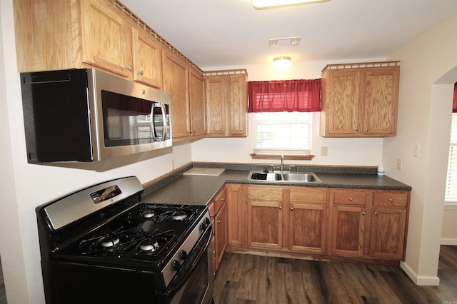 206 E Gum St, Sheridan, AR 72150 - kitchen featuring appliances with stainless steel finishes, dark wood-type flooring, dark countertops, and brown cabinets