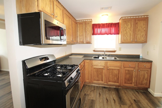 206 E Gum St, Sheridan, AR 72150 - kitchen featuring stainless steel appliances, dark countertops, dark wood-type flooring, and brown cabinetry