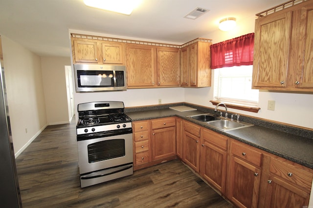 206 E Gum St, Sheridan, AR 72150 - kitchen with appliances with stainless steel finishes, dark countertops, dark wood-style floors, and brown cabinetry