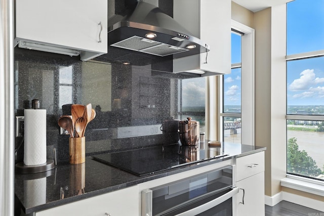 521 President Clinton Ave Unit 1101, Little Rock, AR 72201 - kitchen featuring ventilation hood, white cabinets, stainless steel oven, backsplash, and dark stone countertops