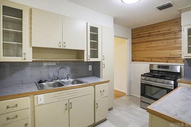 2615 Crouchwood, Little Rock, AR 72207 - kitchen featuring stainless steel range with gas stovetop, backsplash, light countertops, light flooring, and wood walls