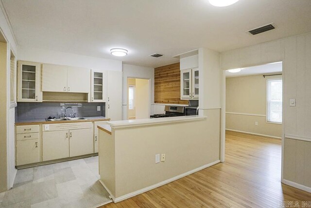 2615 Crouchwood, Little Rock, AR 72207 - kitchen featuring stainless steel appliances, decorative backsplash, glass insert cabinets, light countertops, and light wood-style flooring