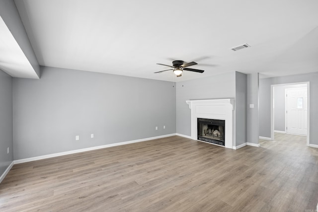 unfurnished living room featuring a ceiling fan, light wood-type flooring, and a fireplace