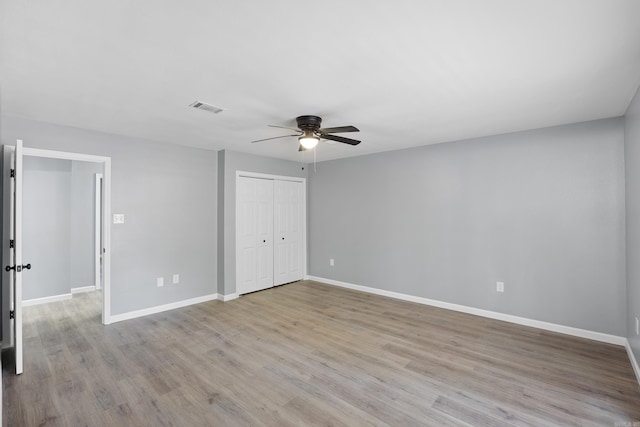 unfurnished bedroom with wood finished floors, a closet, and ceiling fan
