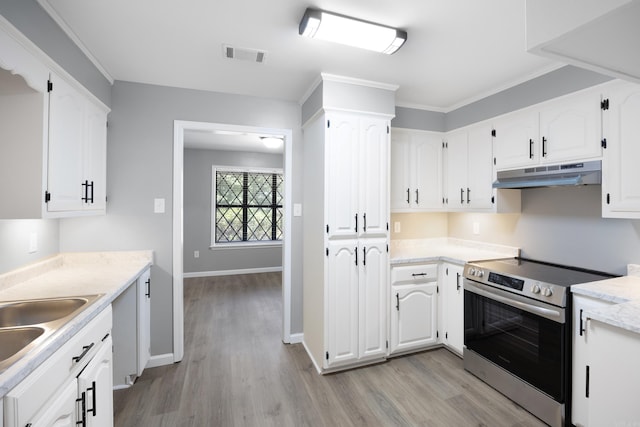 kitchen with under cabinet range hood, stainless steel range with electric cooktop, light wood-style flooring, white cabinets, and ornamental molding