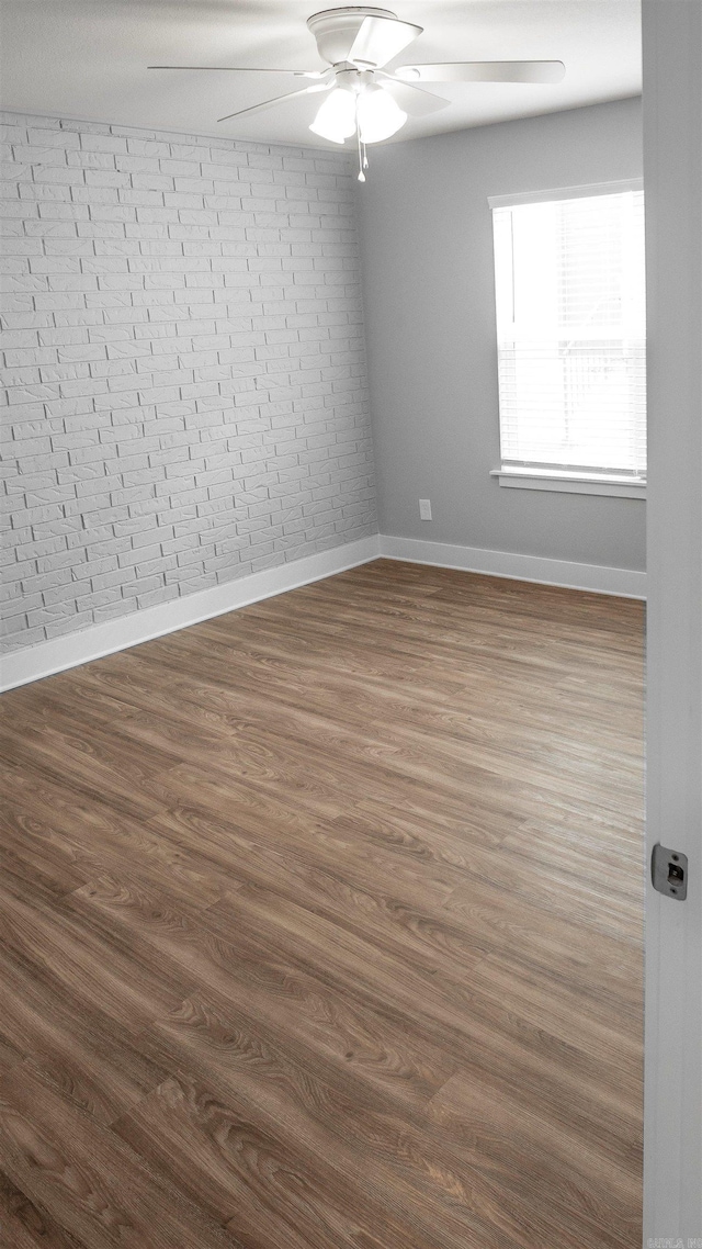 300 W Pleasure Ave, Searcy, AR 72143 - spare room with a ceiling fan, brick wall, and dark wood-type flooring