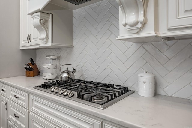 21 Ensbury Pl, Little Rock, AR 72223 - kitchen with stainless steel gas stovetop, white cabinets, decorative backsplash, and light stone counters