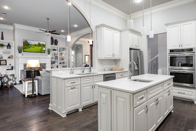 21 Ensbury Pl, Little Rock, AR 72223 - kitchen featuring appliances with stainless steel finishes, a ceiling fan, arched walkways, a kitchen island with sink, and ornamental molding