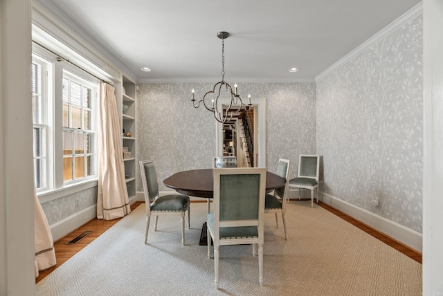 1811 N Jackson St, Little Rock, AR 72207 - dining room with wood finished floors, a chandelier, wallpapered walls, and crown molding