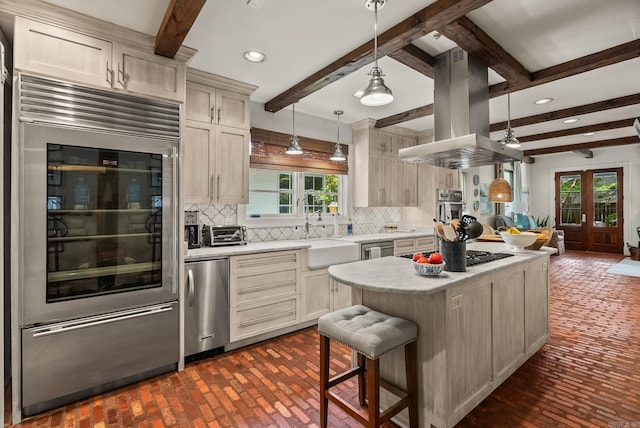 1811 N Jackson St, Little Rock, AR 72207 - kitchen featuring stainless steel appliances, island exhaust hood, brick flooring, light countertops, and backsplash