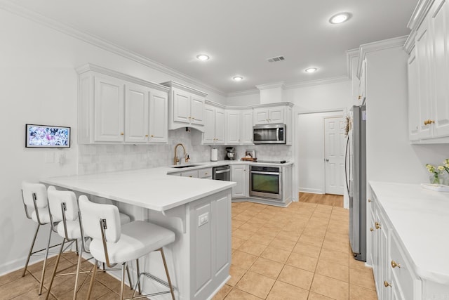 7 Chalamont Way, Little Rock, AR 72223 - kitchen featuring appliances with stainless steel finishes, a peninsula, white cabinets, tasteful backsplash, and ornamental molding