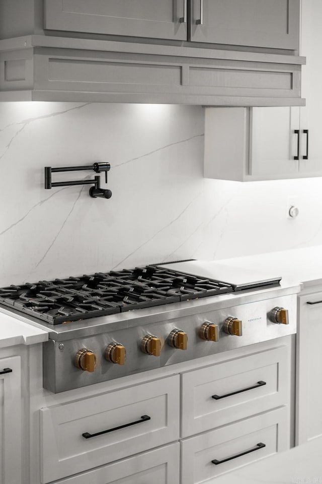 41 Haywood Ct, Little Rock, AR 72223 - kitchen view of decorative backsplash, stainless steel gas cooktop, pot filler, and white cabinetry